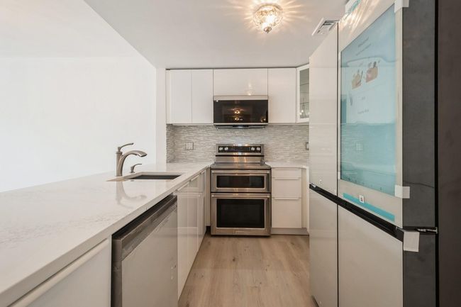 Kitchen featuring appliances with stainless steel finishes, white cabinets, light wood-style floors, backsplash, and modern cabinets | Image 4