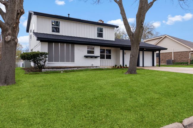 View of front of house featuring a garage, concrete driveway, a chimney, central AC, and a front yard | Image 4