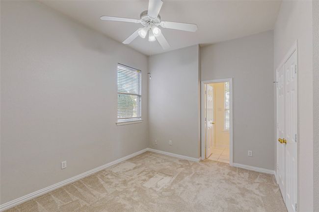 Unfurnished bedroom featuring light colored carpet, baseboards, ensuite bath, and a ceiling fan | Image 29