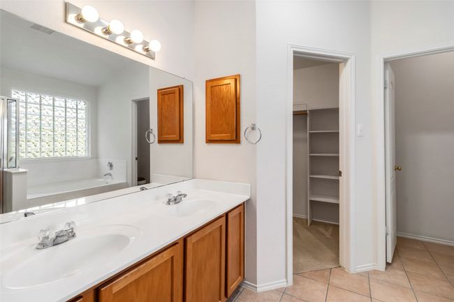 Bathroom featuring a bath, tile patterned floors, double vanity, a walk in closet, and baseboards | Image 23
