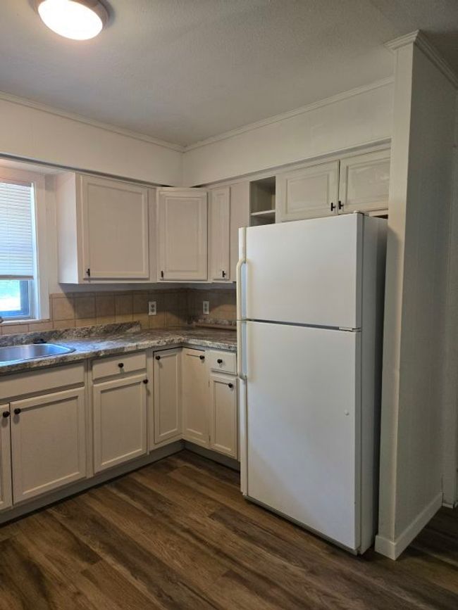 Kitchen featuring freestanding refrigerator, dark wood-type flooring, crown molding, white cabinets, and open shelves | Image 9