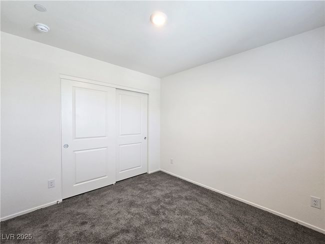 Unfurnished bedroom with dark carpet, baseboards, and a closet | Image 23
