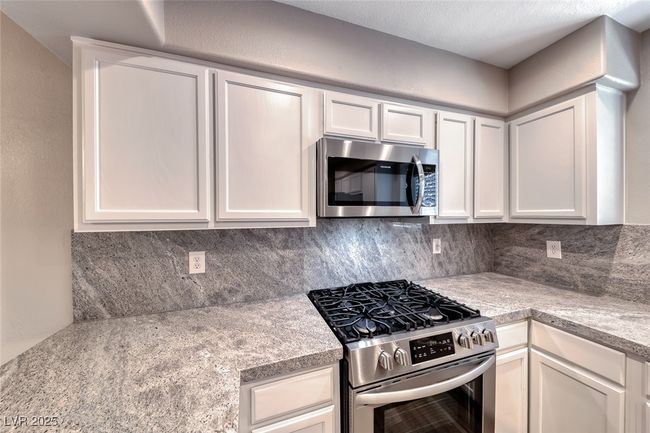 Kitchen featuring stainless steel appliances, decorative backsplash, and light countertops | Image 14