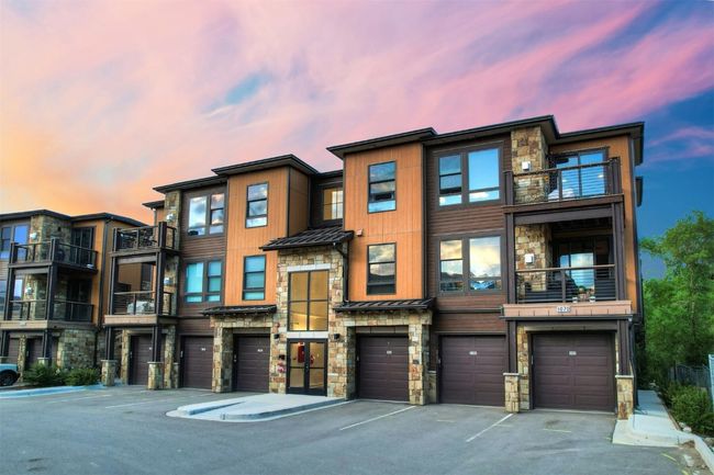 View of property featuring a balcony, stone siding, a standing seam roof, metal roof, and a garage | Image 33