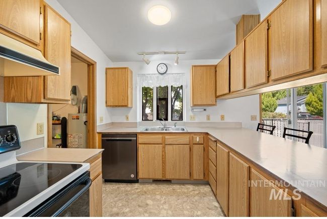 Kitchen featuring electric range, dishwasher, light countertops, track lighting, and under cabinet range hood | Image 7