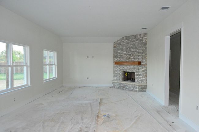 Unfurnished living room with a brick fireplace and baseboards | Image 7