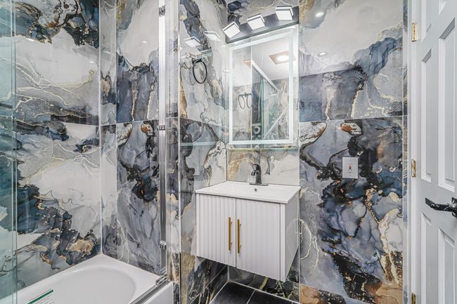 Bathroom with tile walls, vanity, and washtub / shower combination | Image 11