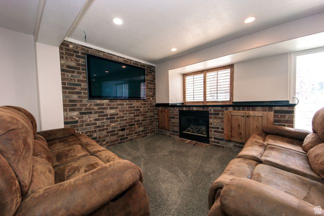 Carpeted living room featuring recessed lighting, a built-in brick fireplace, and a brick wall perfect for hanging your TV for entertainment. | Image 26