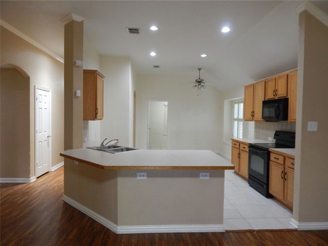 Kitchen featuring black appliances, ceiling fan, arched walkways, a peninsula, and decorative backsplash | Image 9
