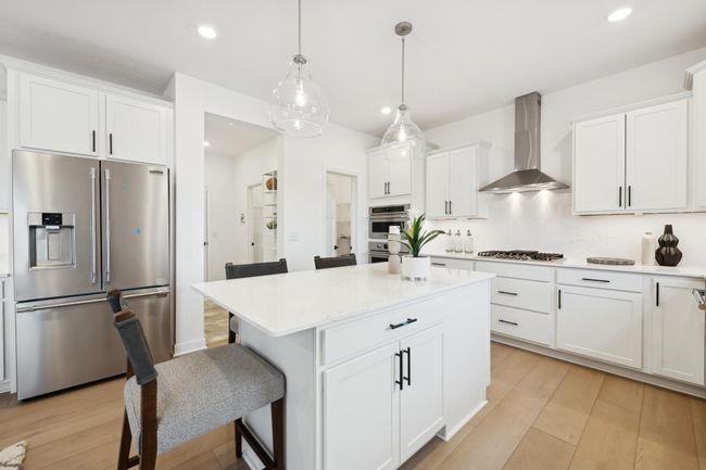 (Photo of decorated model, actual home's finishes will vary) This spacious kitchen features a large center island, quartz countertops, recessed lighting, LVP floors, stainless appliances and more! | Image 5