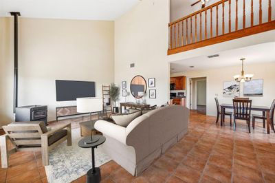 Living room featuring high vaulted ceiling, a wood stove, and tile flooring | Image 3