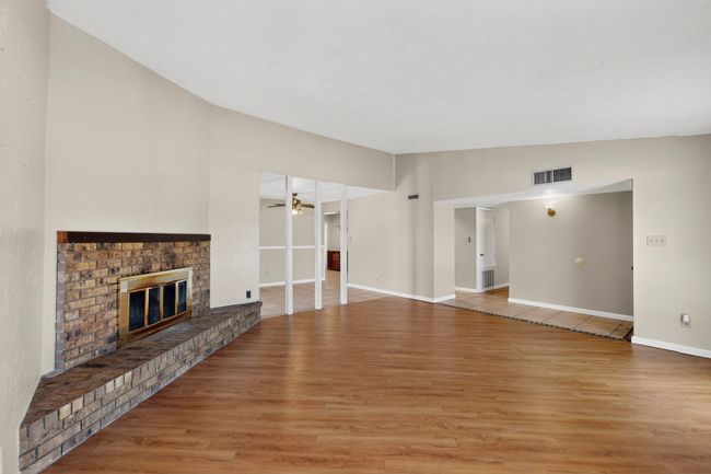 Unfurnished living room featuring a brick fireplace, wood finished floors, and a ceiling fan | Image 5
