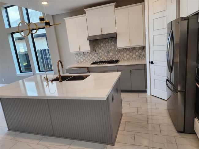 The kitchen have many details like hardware and 8 Ft doors, the herringbone pattern on the back splash the combination of cabinetry, surrounded by double panel windows which are upgrades on this home in order to bring the modern aspect and allow the flow of the natural light. | Image 8