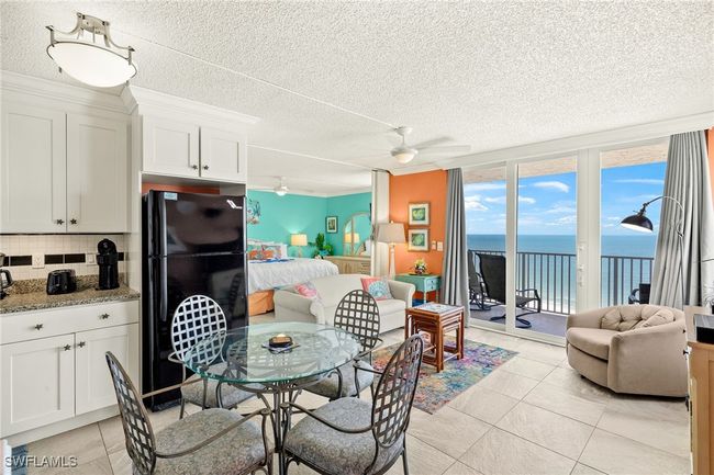 Dining room with a water view, a wall of windows, a textured ceiling, ceiling fan, and light tile patterned flooring | Image 5