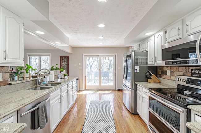 kitchen with tasteful backsplash, a sink, white cabinets, appliances with stainless steel finishes, and recessed lighting | Image 13