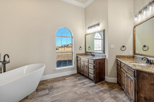 Bathroom with ornamental molding, a freestanding bath, two vanities, wood finished floors, and baseboards | Image 15
