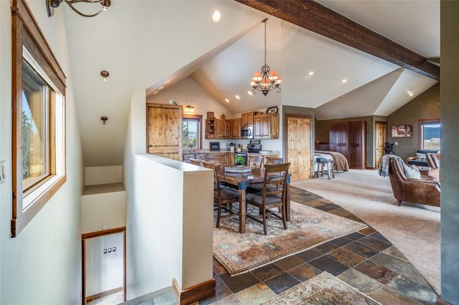 Caretaker Quarters / Guest House. Dining area featuring beamed ceiling, a notable chandelier, stone tile floors, and high vaulted ceiling | Image 73