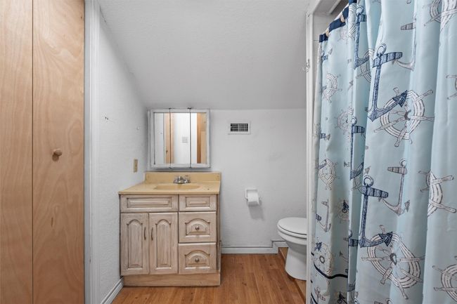 Bathroom with visible vents, baseboards, wood finished floors, toilet, and lofted ceiling | Image 14