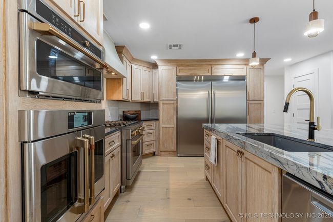 Main kitchen with luxury counters, luxury appliances, bar seating, and custom cabinets | Image 22