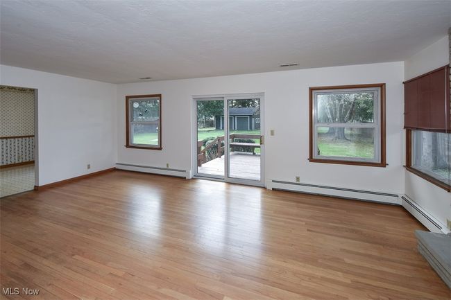 Unfurnished living room featuring baseboards, light wood-type flooring, visible vents, and baseboard heating | Image 18