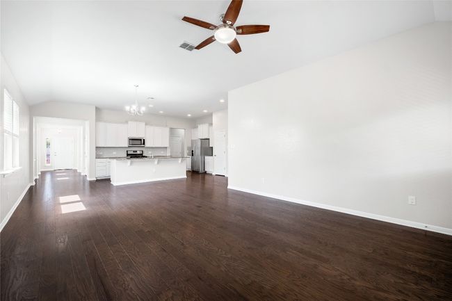 Unfurnished living room with lofted ceiling, a chandelier, a ceiling fan, dark wood-type flooring, and recessed lighting | Image 21