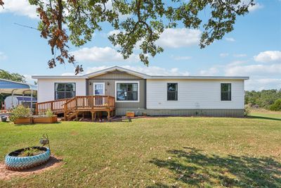 Rear view of house with a yard and a wooden deck | Image 1