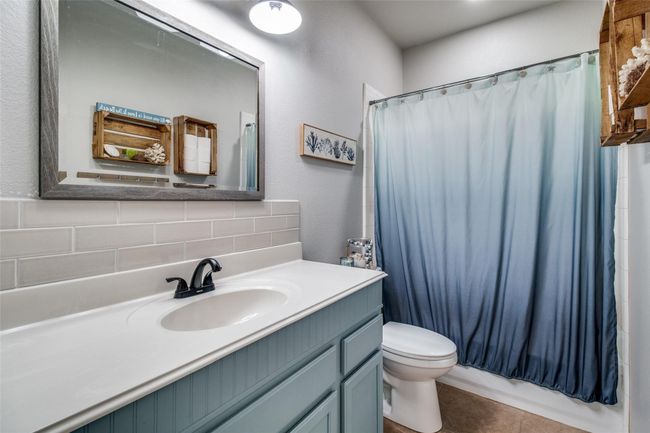 Full bath with decorative backsplash, toilet, vanity, and a shower with shower curtain | Image 20