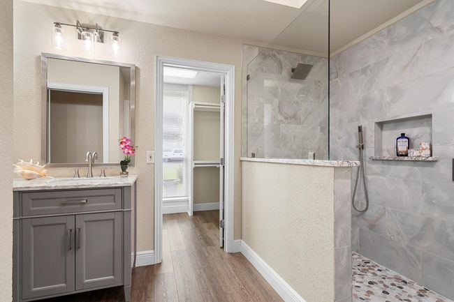 The primary bathroom has a doorless walk in shower with beautiful tile work and large walk in closet. | Image 21