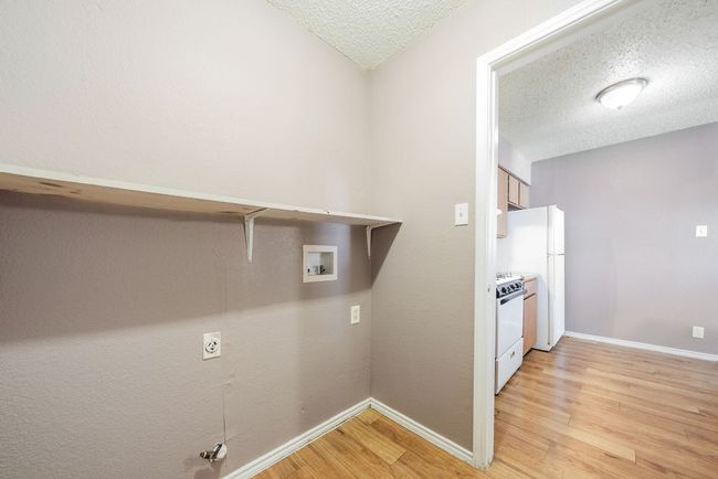 Washroom with light wood-type flooring, a textured ceiling, and hookup for a washing machine | Image 19