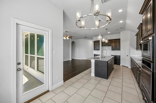 Kitchen featuring a sink, decorative backsplash, arched walkways, and stainless steel appliances | Image 15