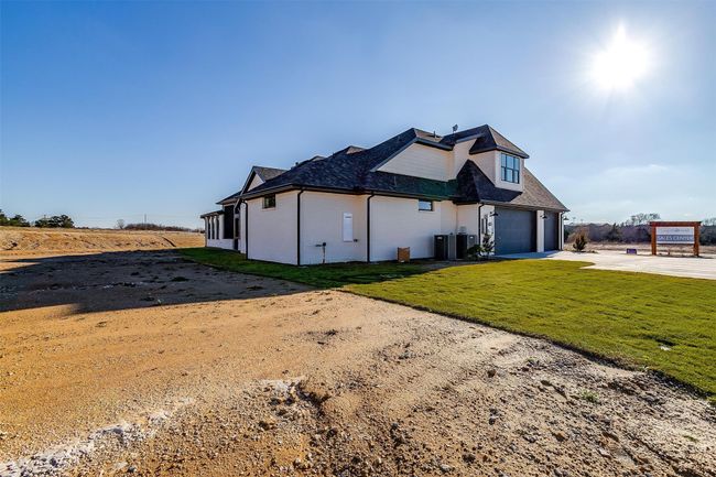 View of front of property featuring central air condition unit, a front yard, and a garage | Image 34