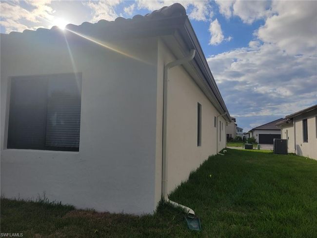 View of home's exterior featuring stucco siding, central AC unit, and a yard | Image 31