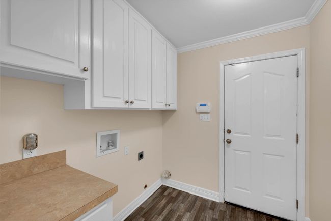 Laundry room with cabinet space, hookup for an electric dryer, ornamental molding, hookup for a washing machine, and dark wood-type flooring | Image 28