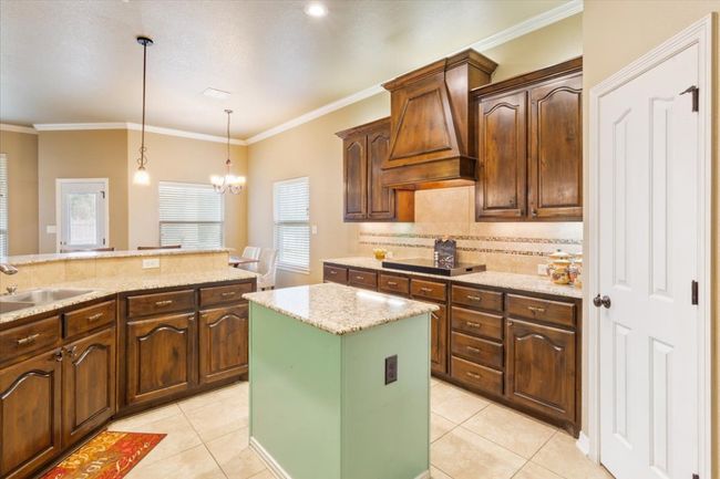 Kitchen featuring a sink, black electric cooktop, custom exhaust hood, and light tile patterned flooring | Image 16