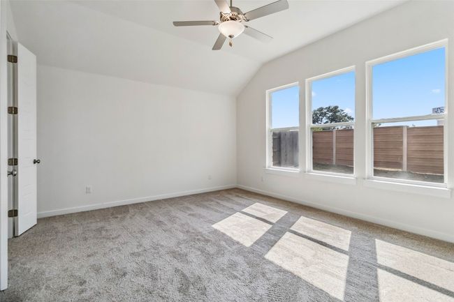 Carpeted spare room featuring lofted ceiling and ceiling fan | Image 21