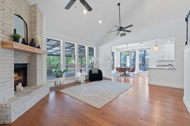Living area featuring ceiling fan, high vaulted ceiling, a fireplace, wood finished floors, and recessed lighting | Image 12