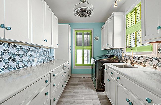 Laundry room featuring light wood-style flooring, a sink, baseboards, washer and dryer, and cabinet space | Image 17