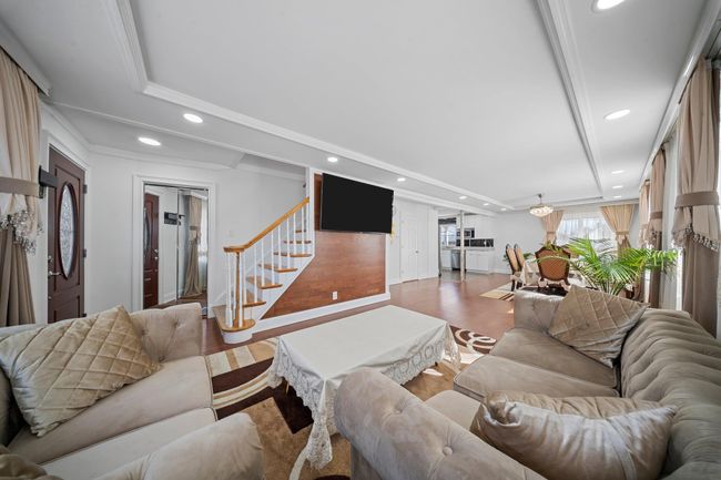 Living area with stairs, ornamental molding, recessed lighting, wood finished floors, and a raised ceiling | Image 9