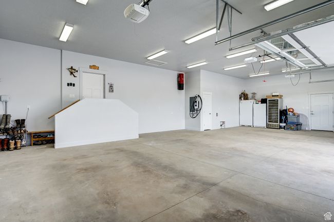 Garage featuring a garage door opener and freestanding refrigerator | Image 109