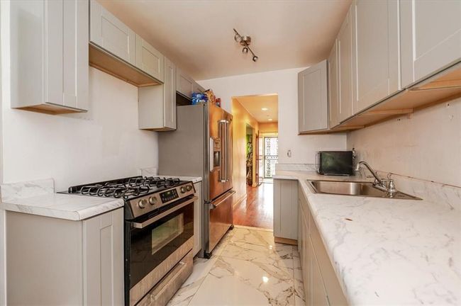 Kitchen featuring light hardwood / wood-style flooring, gray cabinets, track lighting, stainless steel range with gas stovetop, and sink | Image 6