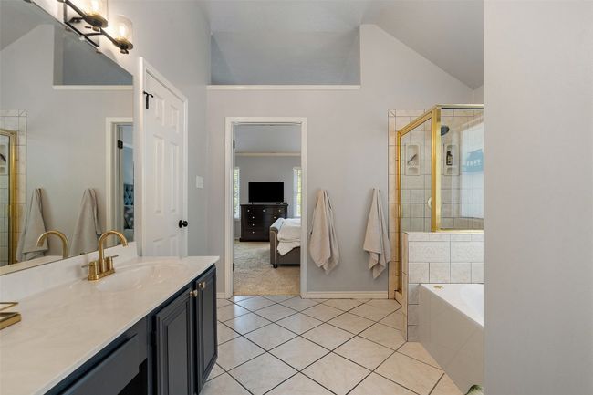 Full bath with tile patterned floors, vaulted ceiling, tiled shower, vanity, and a bath | Image 24