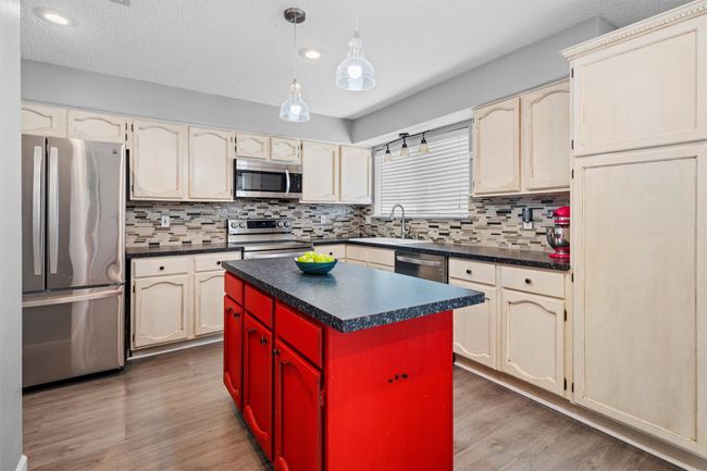 Kitchen with a sink, dark countertops, wood finished floors, and appliances with stainless steel finishes | Image 6