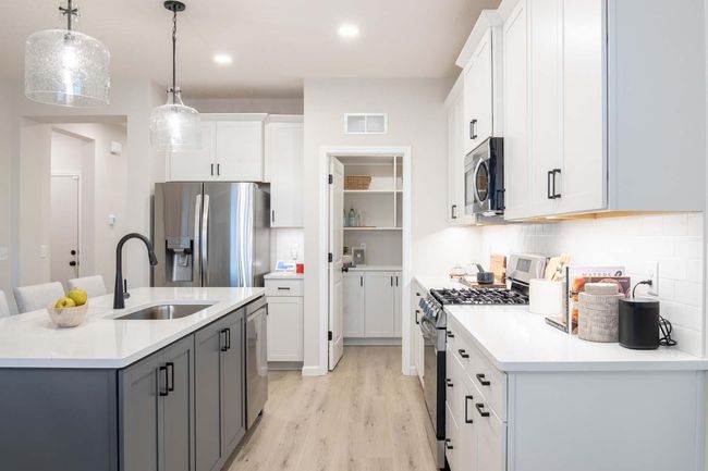 The kitchen features elegant white perimeter cabinets that create a timeless look. The walk-in pantry with cabinets and shelving will keep the busiest family organized. Photos are from previously built home; options & features will vary. | Image 7