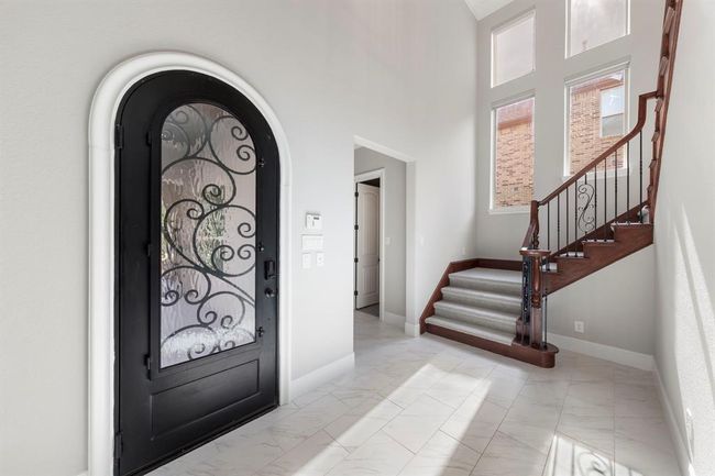 This bright, welcoming entryway showcases new tile floors, fresh interior paint, and elegant ironwork, all enhanced by a state-of-the-art Control4 smart home system and upgraded alarm for modern peace of mind. | Image 5