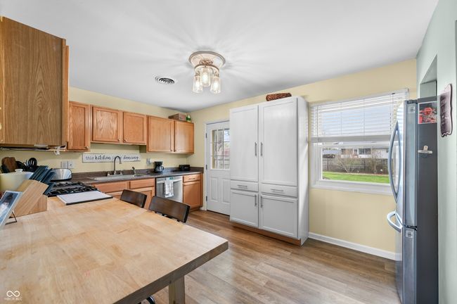 kitchen with a sink, stainless steel appliances, light wood finished floors, baseboards, and visible vents | Image 16