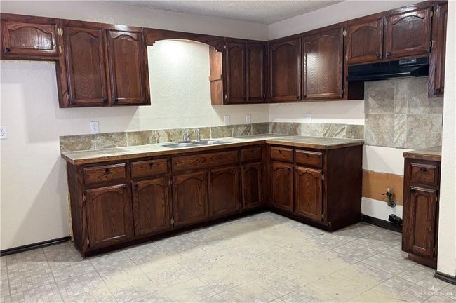 Kitchen with sink, dark brown cabinets, and a textured ceiling | Image 7