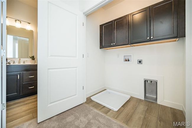 Laundry area featuring cabinet space, hookup for an electric dryer, washer hookup, and light wood finished floors | Image 17