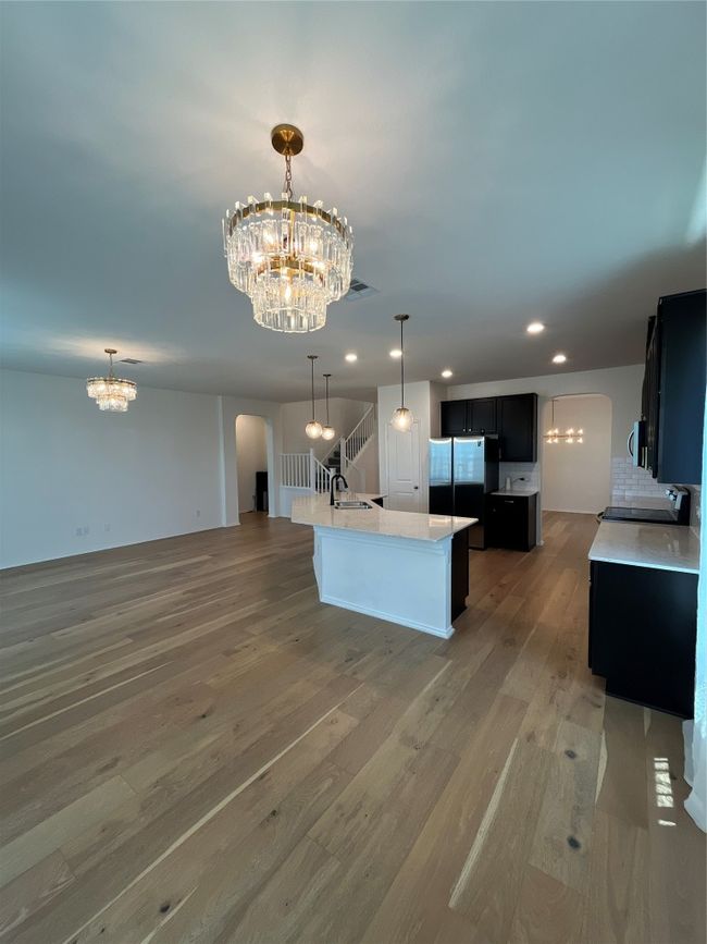 Kitchen with an inviting chandelier, arched walkways, a sink, and fridge | Image 11
