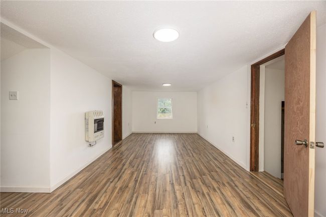 Unfurnished living room with heating unit, wood finished floors, and baseboards | Image 7