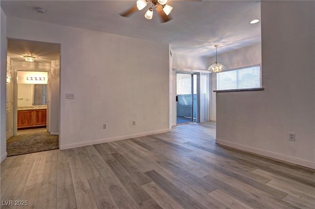 Unfurnished room with wood finished floors, a ceiling fan, a chandelier, baseboards, and a smoke detector | Image 6